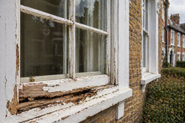 Homeowner attempting a DIY repair on a traditional timber sash window